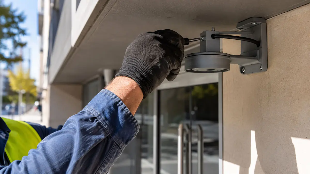 Metwide technician installing a commercial CCTV camera under the awning of a Sydney office building entry.