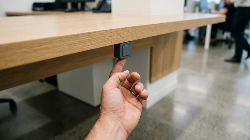 Hand reaching for a discreet duress button under a Sydney CBD reception counter