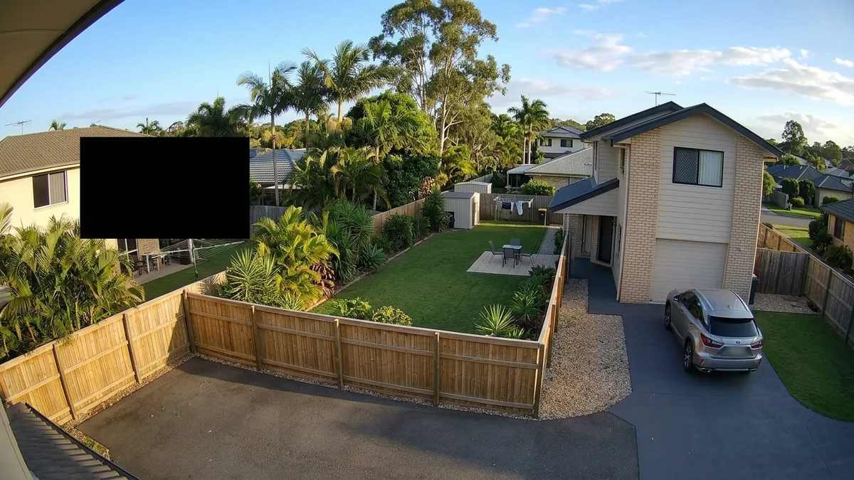 Brisbane home CCTV view of a backyard and driveway with a privacy mask blacking out the neighbour's property across the timber paling fence.